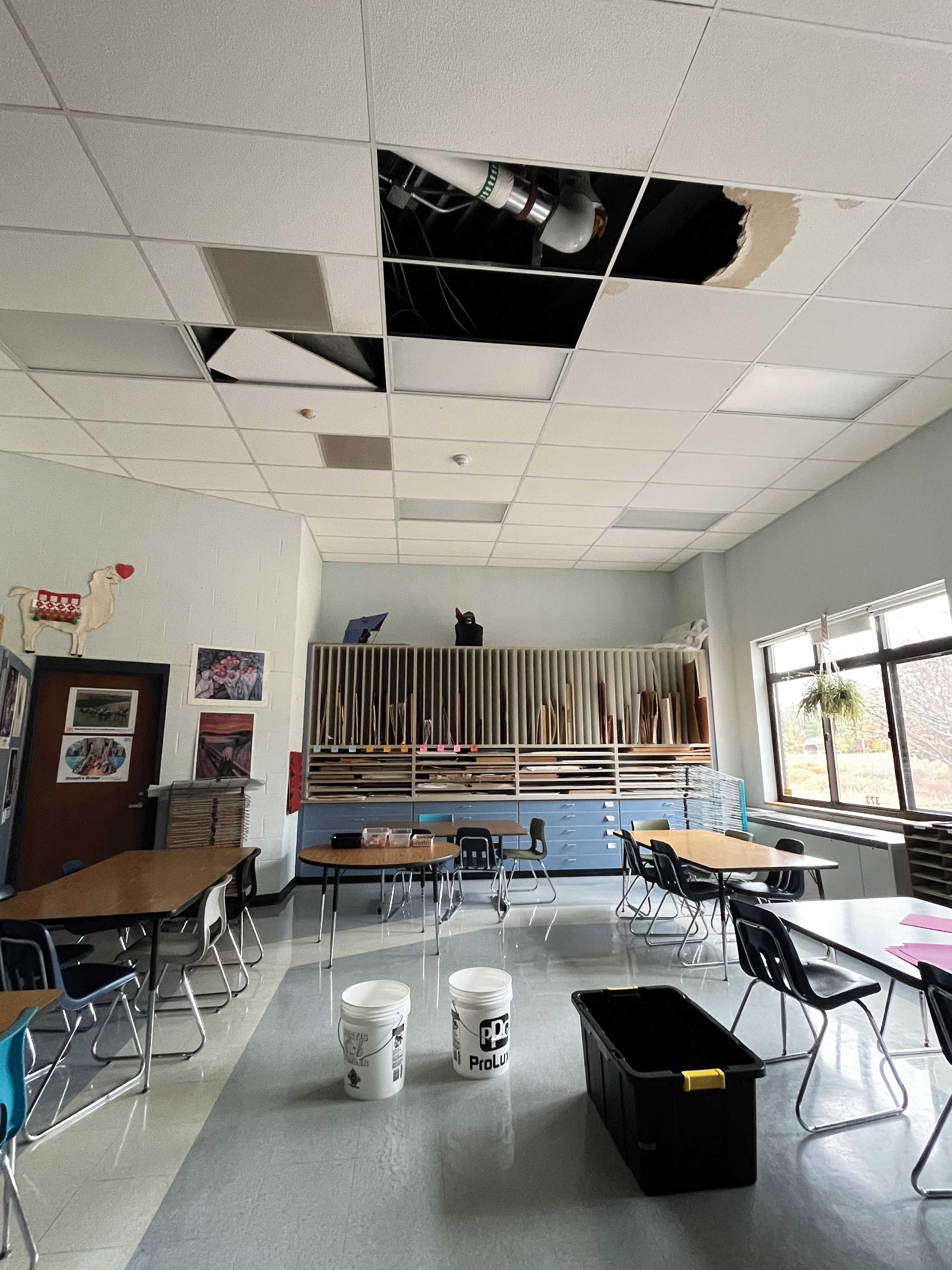 ceiling tiles removed in art room and buckets on the floor to catch water leaking from the roof
